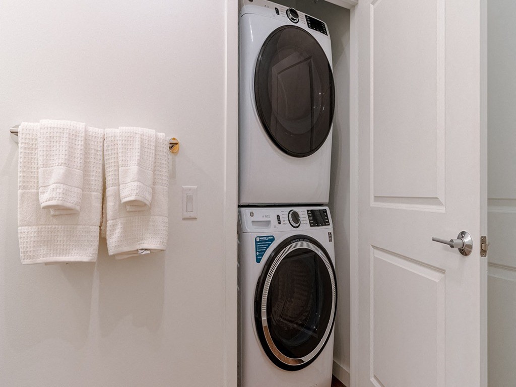 a white washer and dryer in a laundry room with white towels